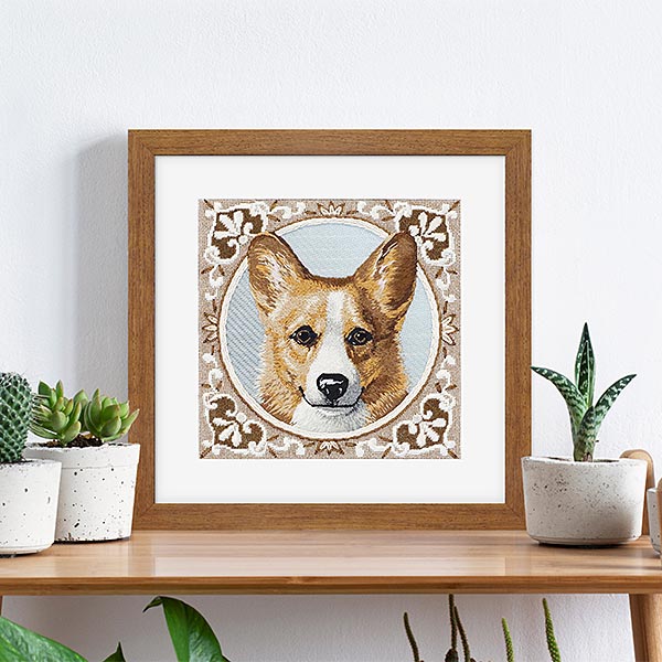 Custom Frame needlepoint of corgi framed in rustic walnut frame and white mat, sitting on a table with potted cactus Hall of Frames Arizona