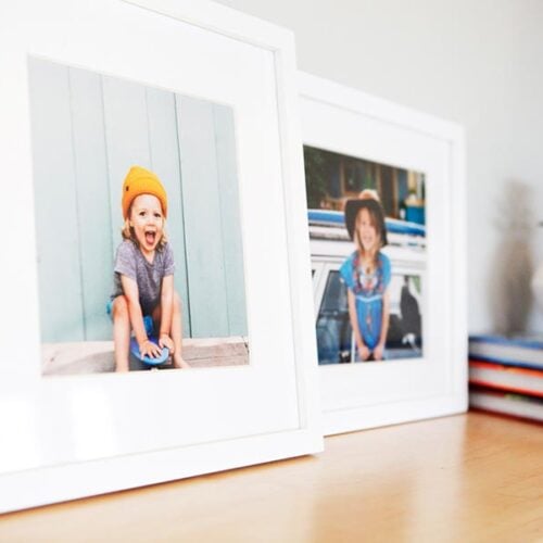 framed photographs of little girls, framed in gallery white frames and white mats, resting on a shelf with books and a plant Hall of Frames Arizona
