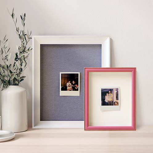 Readymade framed polaroid photos styled on a table with greenery