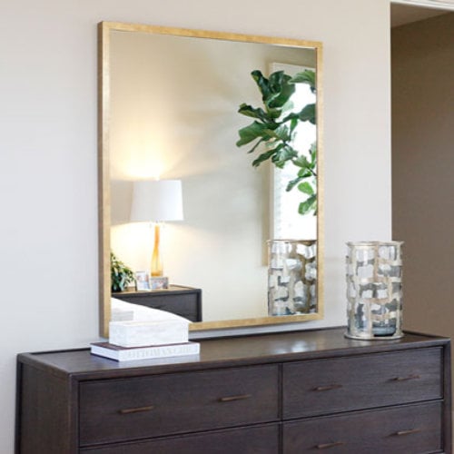 Photo of a custom framed gold mirror in a bedroom