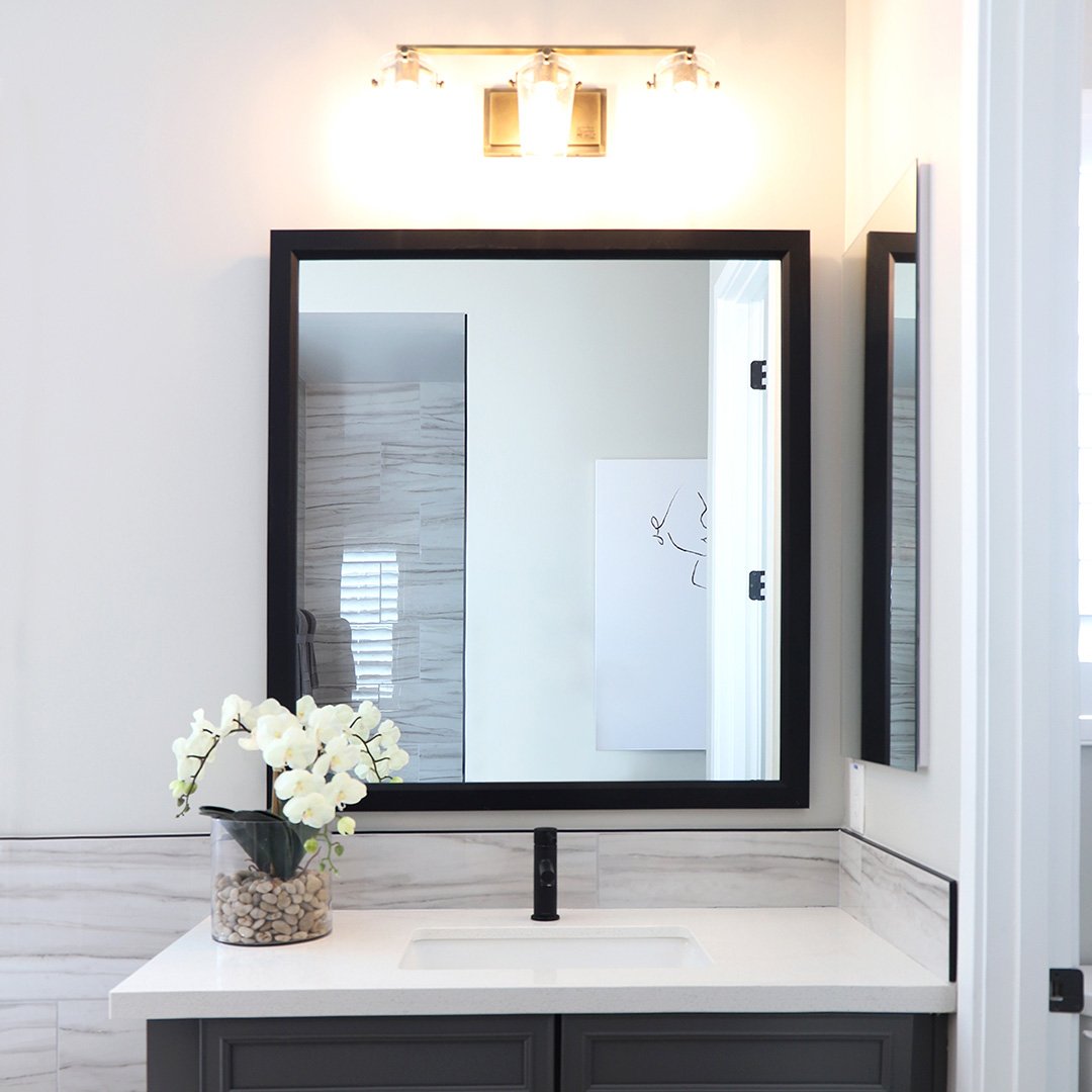 A photo of a custom framed bathroom mirror over a vanity for a business customer by Hall of Frames