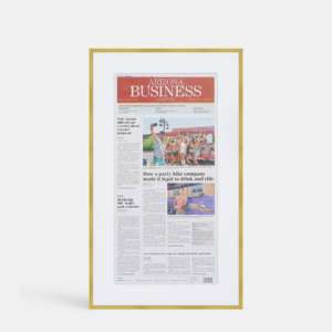 A photo of a custom framed newspaper article in a thin modern gold brass by Hall of Frames.