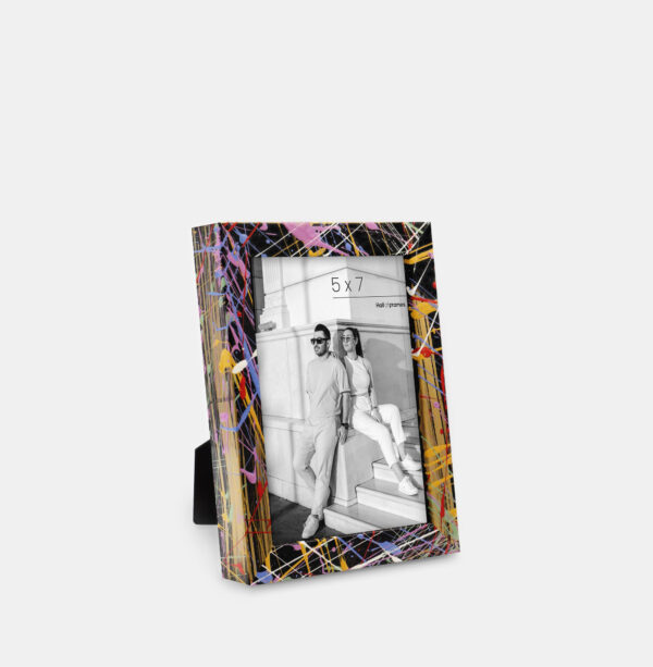 A paint splatter frame in the color Acro Mist featuring a modern, architectural photo of a couple.