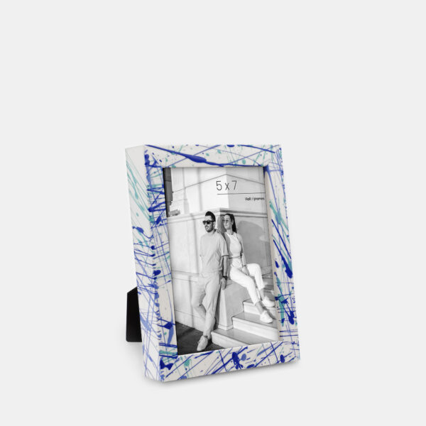 A paint splatter frame in the color Azure Flow featuring a modern, architectural photo of a couple.