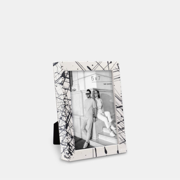 A paint splatter frame in the color Metro Fade featuring a modern, architectural photo of a couple. 