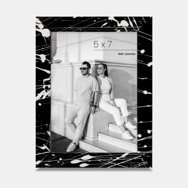 A paint splatter frame in the color Night Hush featuring a modern, architectural photo of a couple. 