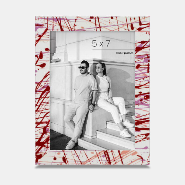 A paint splatter frame in the color Rebel Rose featuring a modern, architectural photo of a couple. 
