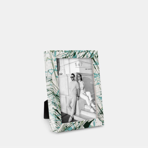 A paint splatter frame in the color Verde Mint featuring a modern, architectural photo of a couple. 