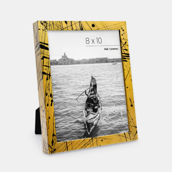 A paint splatter frame in the color Oro Drip featuring a photo of a couple in a gondola. 