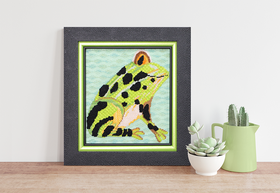 A photo of a frog needlepoint framed with triple stack frames