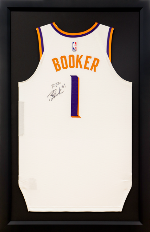 Framed Devin Booker #1 Phoenix Suns jersey, white with orange text and a signed personal message.