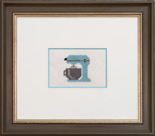 Small cross-stitch of a light blue stand mixer in a wide-matted, dark wood frame.Small cross-stitch of a light blue stand mixer in a wide-matted, dark wood frame.