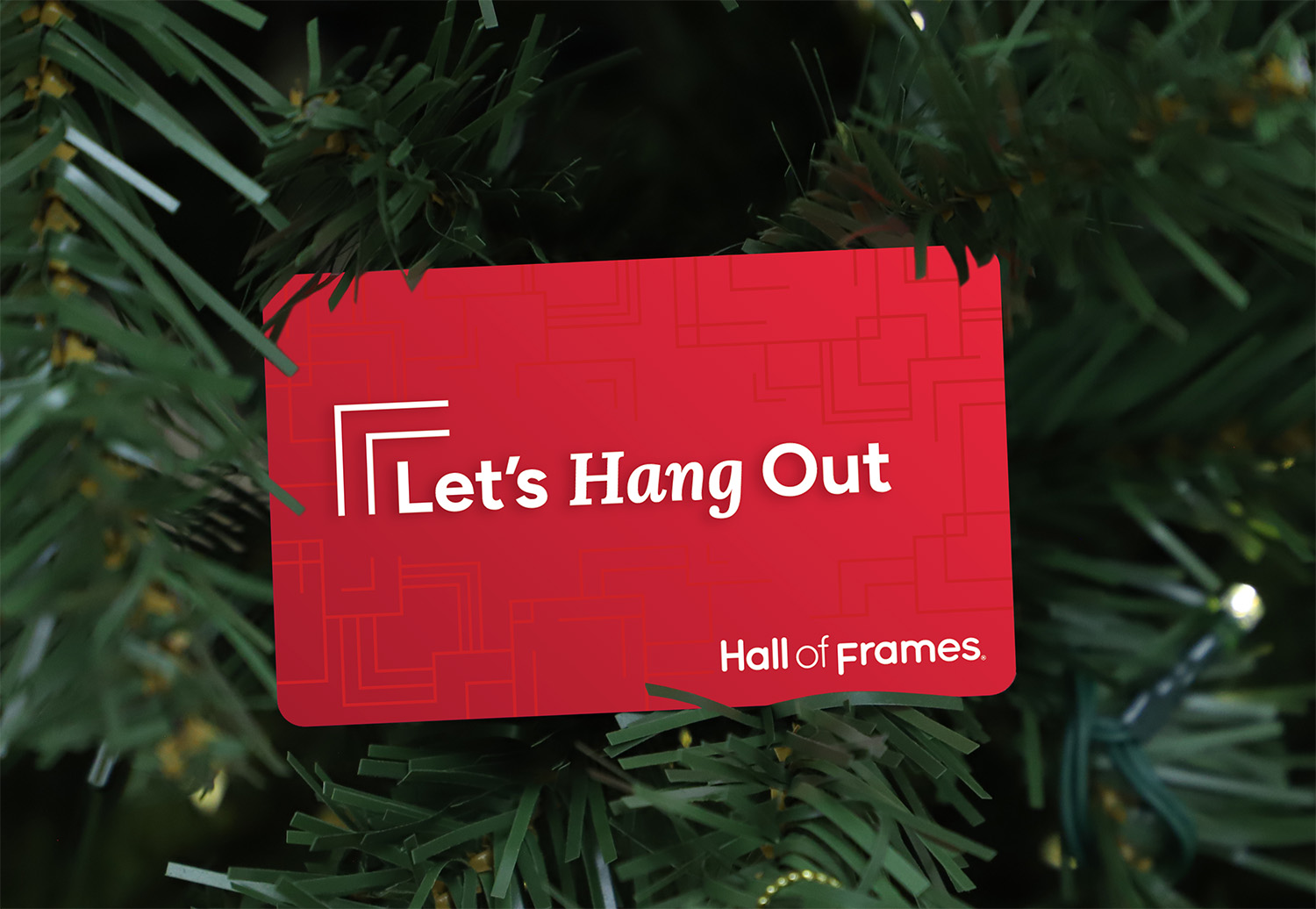 Red Hall of Frames gift card featuring the text "Let's Hang Out" nestled in the green branches of a Christmas tree.