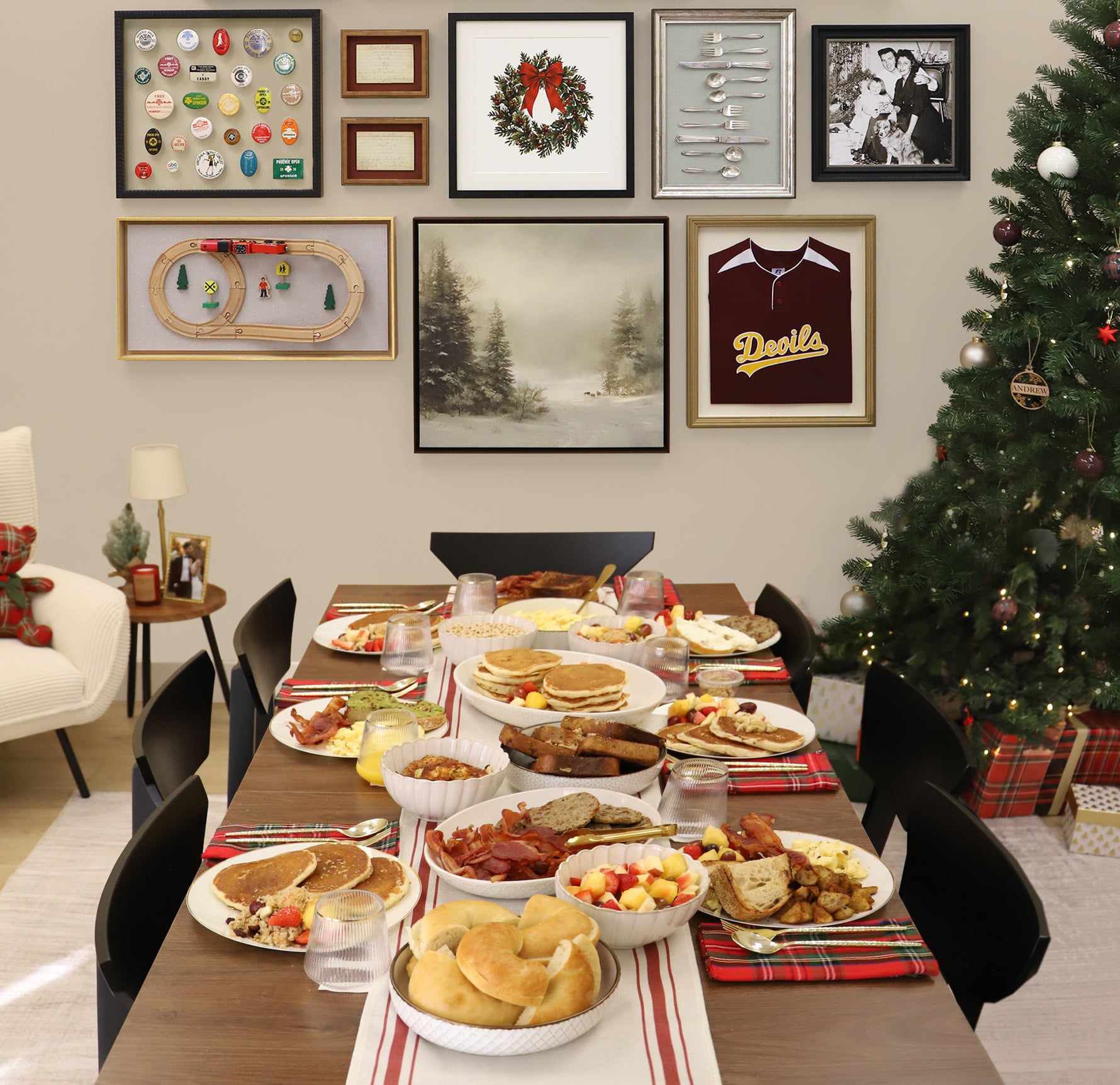 Festive breakfast spread on a dining table next to a Christmas tree, set beneath a custom gallery wall of shadowboxes and framed artwork